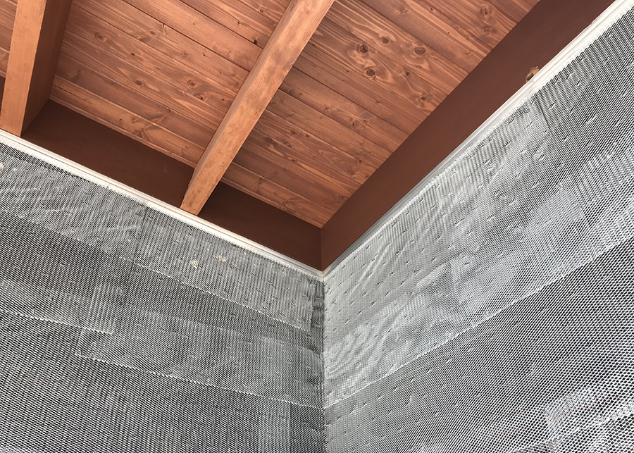 The interior of the restroom, exposed wood panels line the ceiling, stainless steel mesh on the walls